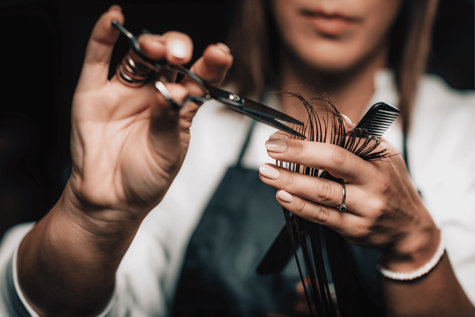 A hairdresser carefully cutting hair with scissors and a comb, showcasing detailed technique.