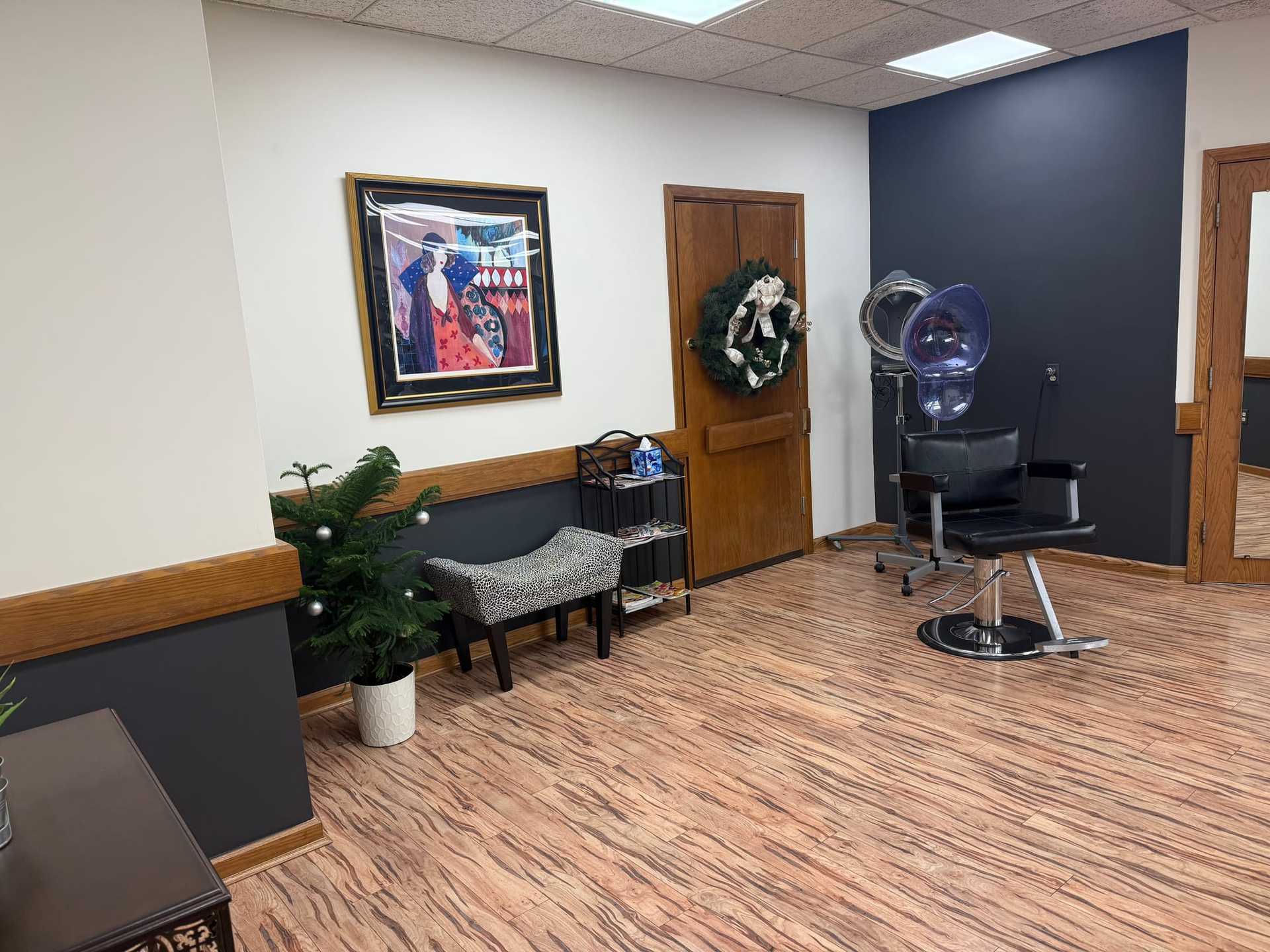 Hair salon corner with styling chair, wall art, and wreath on the door.